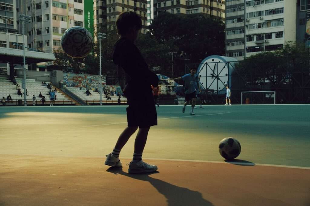 Adolescente em silhueta praticando futebol em uma quadra ao ar livre